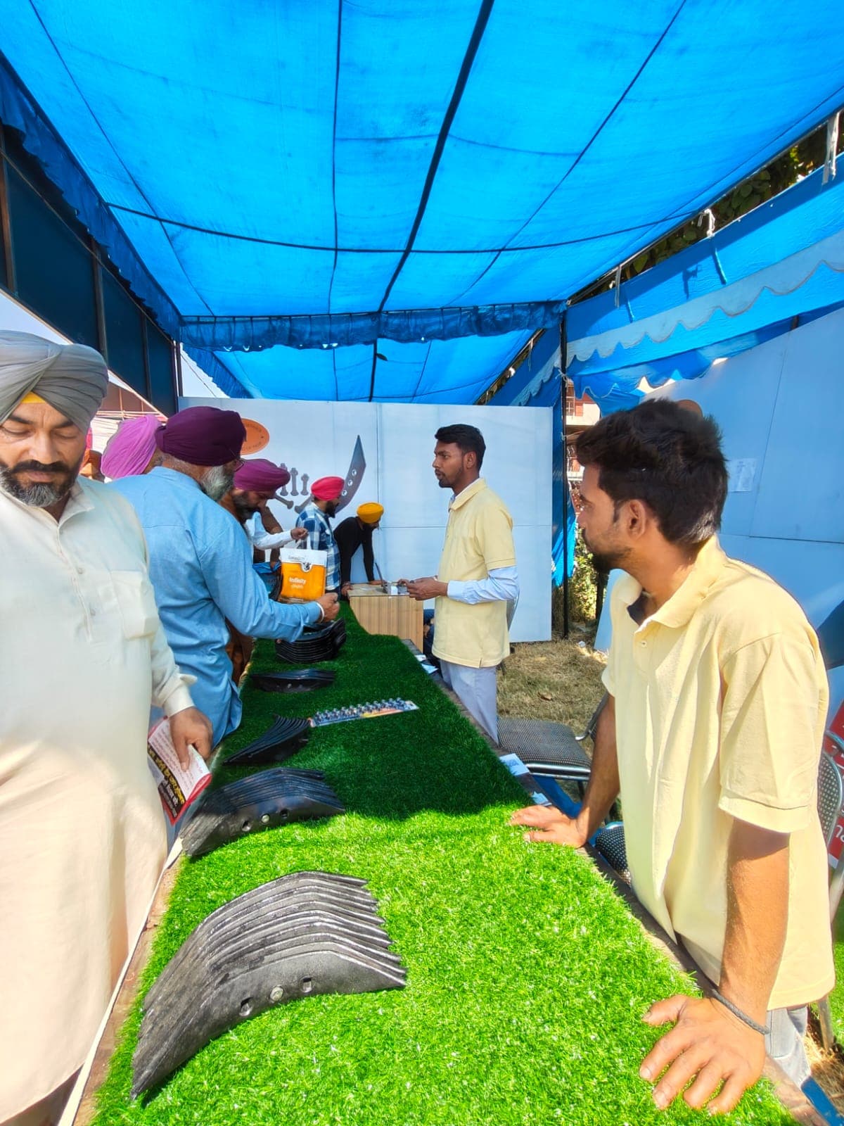 Farmers reviewing cultivator shovels laid out at an Aggarwal Industries stall